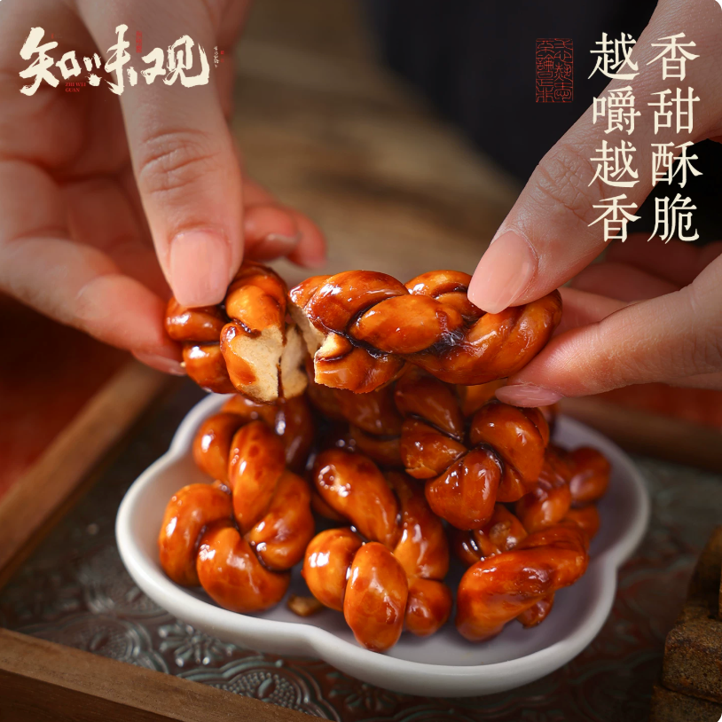 Hands holding a plate of stacked caramelized brown sugar mahua snacks, emphasizing heritage craftsmanship and premium Asian delicacies.