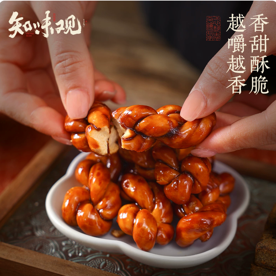 Hands breaking apart a Zhiweiguan brown sugar mahua piece showing crispy layered texture — fragrant, sweet and crunchy
