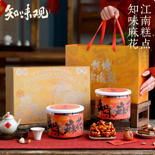 Zhiweiguan Brown Sugar Mahua gift box with golden gift bag, two orange tins and mahua pieces displayed on festive red table setting
