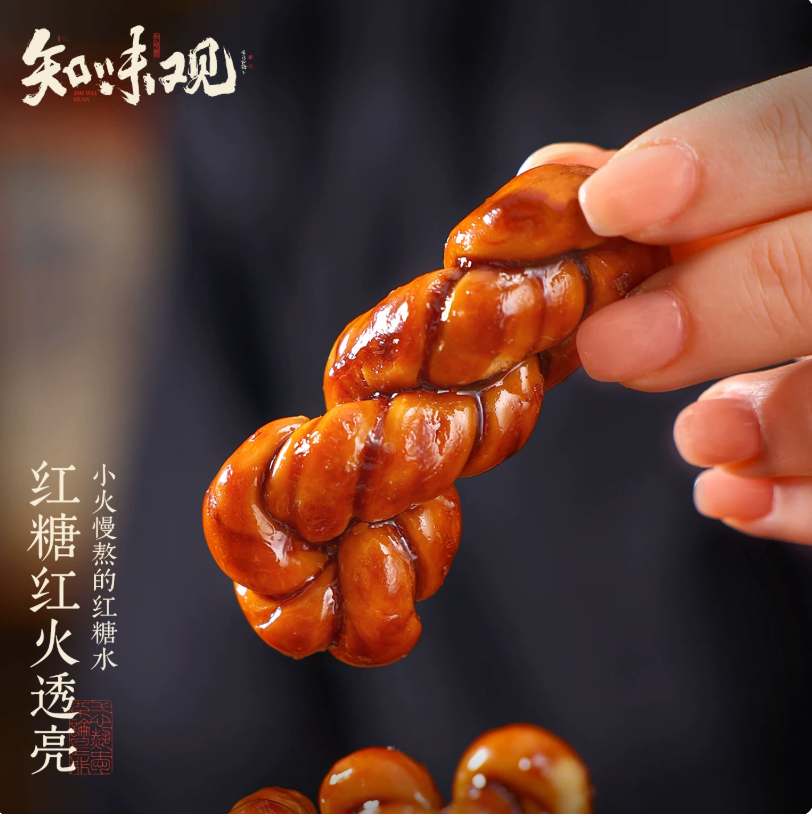 Close-up of a single Zhiweiguan brown sugar twist pastry held by fingers, showing its translucent, slow-simmered caramel glaze.