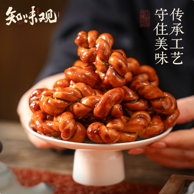 A mini Chinese dough twist being broken in half by hands, displaying its perfectly crispy, airy, and golden internal pastry texture.